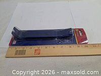 Blue plastic pry bar in unopened package with ruler for scale