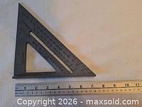 Black plastic triangular set square alongside metal ruler for scale