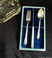Fork and spoon inside blue velvet box with plastic cover showing 1847 Rogers Bros. branding