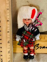 Front view of Scottish bagpiper ornament next to ruler showing size