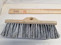 Top view of scrub brush head showing bristles, plastic block and threaded socket alongside ruler for scale