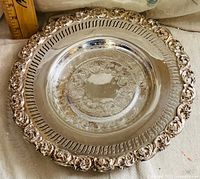 Front view of silver-plated dish showing pierced rim, floral border, and engraved center