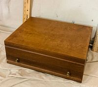 Closed wooden silverware chest showing exterior finish and brass knobs