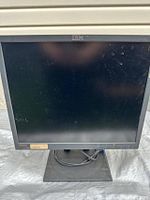 Front view of IBM ThinkVision monitor with stand and cables visible