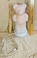 Front view of teddy bear lamp beside rulers showing ~12 in height