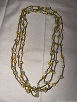 Full view of long multi-strand necklace showing bead colors and gold rope chain