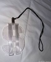 Front view of clear plastic dollar sign pendant with black cord