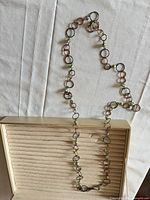 Full view of long ring-link necklace laid out to show length and design