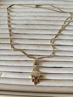 Full view of necklace laid flat, showing double chains and pendant