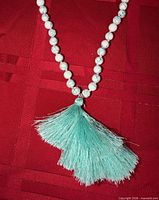 Close-up of beads showing white marbled pattern and mint green tassel