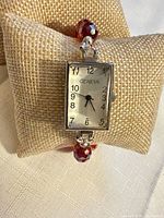 Front view of Geneva watch on cushion showing dial and part of red crystal band