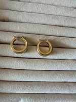 Pair of full circular gold-tone hoops on display pad