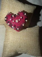 Front view of hot pink felt heart brooch on display pillow
