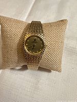 Front view of complete gold-tone watch on display pillow