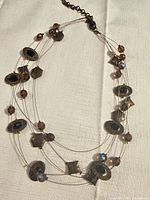 Full view of multi-strand necklace laid flat showing beads, charms and clasp