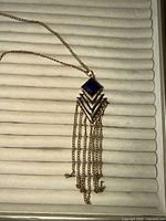 Front view of entire necklace showing chain, purple stone and tassel pendant