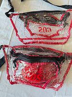 Front view of both clear red fanny packs showing CDS logo, pockets, straps