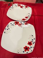 two square white dinner plates with red and blue flowers design