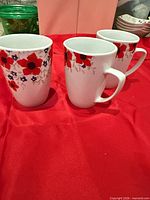 Three white Gibson floral mugs on red cloth