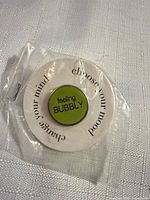 Front view of lime green enamel pin on display card in plastic