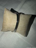 Cuff bracelet on display pillow, showing overall form and silver-tone finish