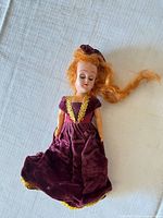 Front full view of vintage doll in burgundy velvet gown with gold trim
