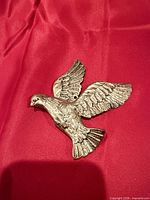 front view of brass-tone flying eagle ornament on red background