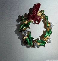 Front view of gold tone wreath brooch showing enamel colors and faux pearls