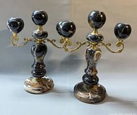 Front view of both stone and brass three-arm candelabras