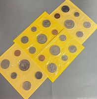 Four yellow-sleeved coin sets with six coins each