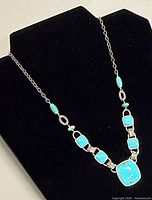 Full view of necklace on display form showing turquoise cabochons and overall design