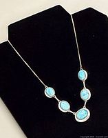 Full view of necklace on display bust showing overall design and drop