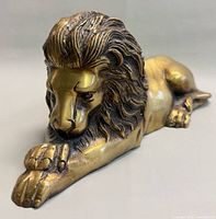 Front three-quarter view of brass lion showing detailed mane and paws