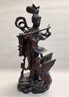 Front view showing full statue, woman with flute and bird on base