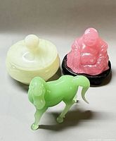 Group shot of rose quartz Buddha, green glass horse and stone lidded bowl