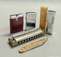 Group shot of harmonica, four lighters and pocket knife