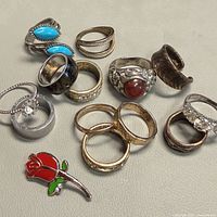 All thirteen rings and rosebud brooch displayed