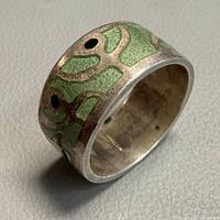 Angled view of ring showing green enamel pattern and black dot accents