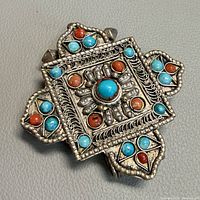 Front of square mandala pendant showing coral and turquoise cabochons and filigree details