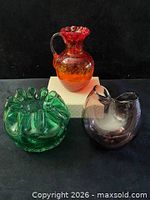 All three hand-blown glass pieces grouped: green bowl, amber pitcher, purple vase