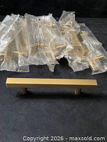 Group of packaged brushed brass handles with one unpackaged handle displayed