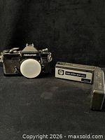 Front view of Nikkormat body with cap, Kodak Ektra 200 camera, and flash accessory