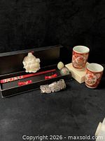 Group shot of all items: two cups, Buddha figurine, chopsticks in box, two stone spheres, metal bracelet