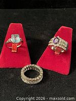 All three rings displayed on red stands and surface