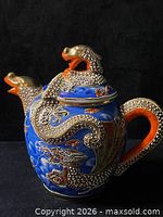 Full view of teapot showing dragon handle, spout, lid and blue background