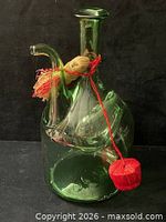 Front view of green glass decanter with tassel