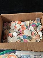 Cardboard box filled with loose multicolored stamps