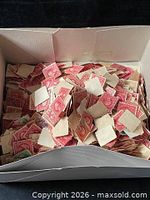 Open box filled with loose red/pink Washington 2-cent U.S. stamps, visible stamp backs and perforations