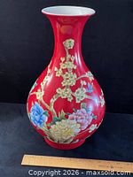 Full view of red ground porcelain vase with floral decoration and ruler for scale