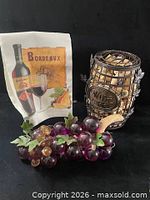 Full lot showing towel, metal cork holder filled with corks, faux grapes